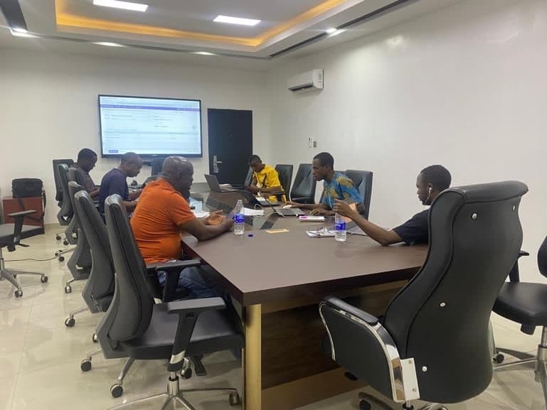 Finance and operations staff working together on laptops in a meeting room with Odoo on the screen